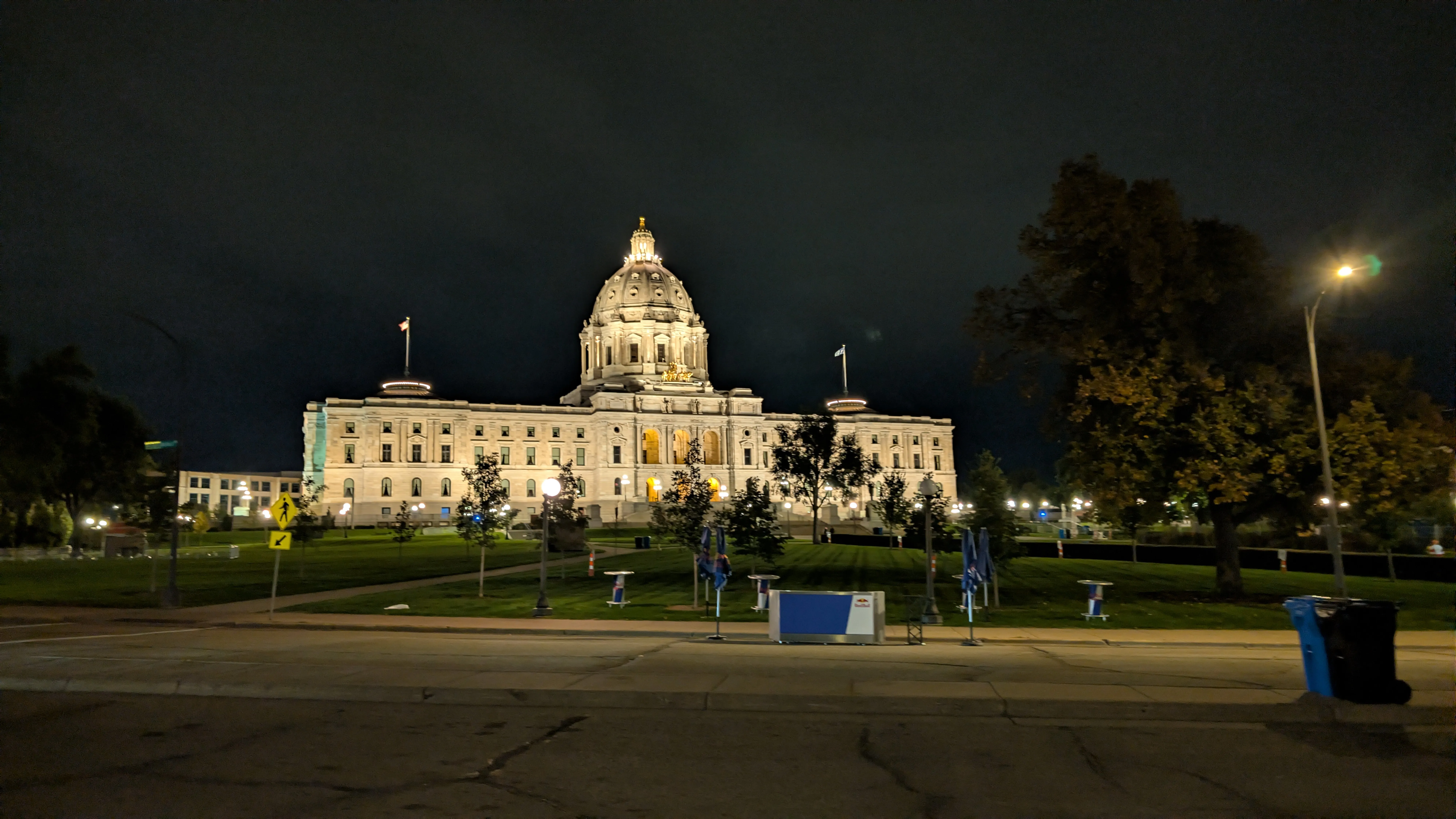 The Minnesota State Capitol lit up in the morning pre-sunrise, with race-weekend tents and signage on the lawn in front